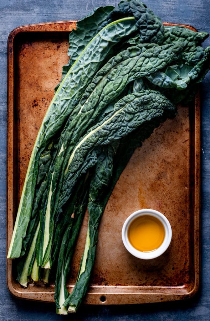 raw kale on baking sheet with olive oil