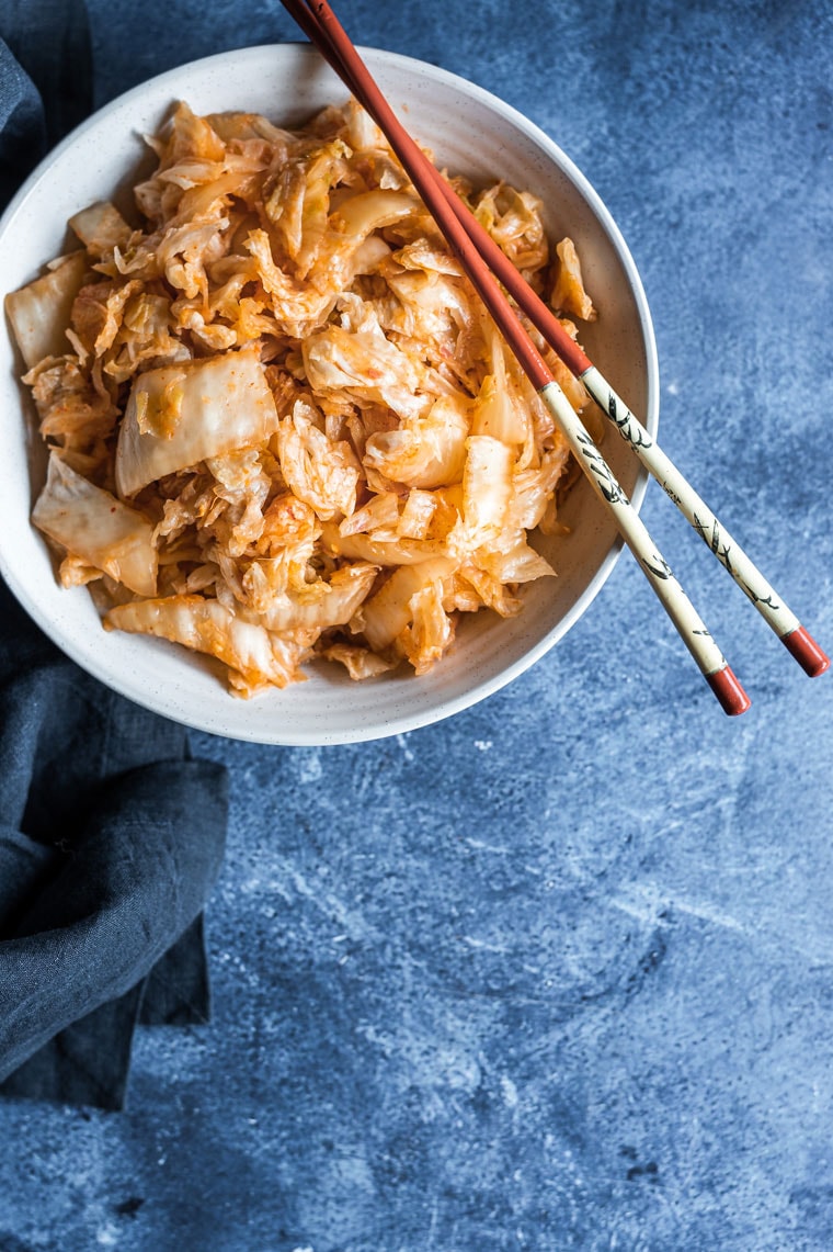 kimchi in a white bowl with blue background