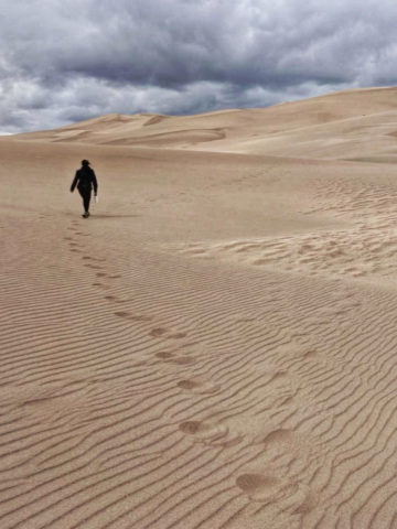person walking through sand dunes
