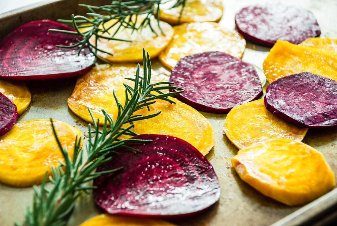 raw beet slices and rosemary on baking sheet 