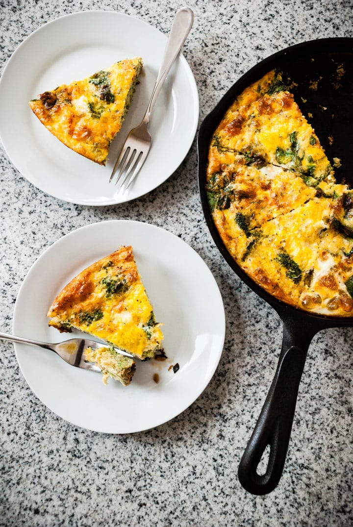 broccoli cheddar frittata in cast iron with 2 slices on plates