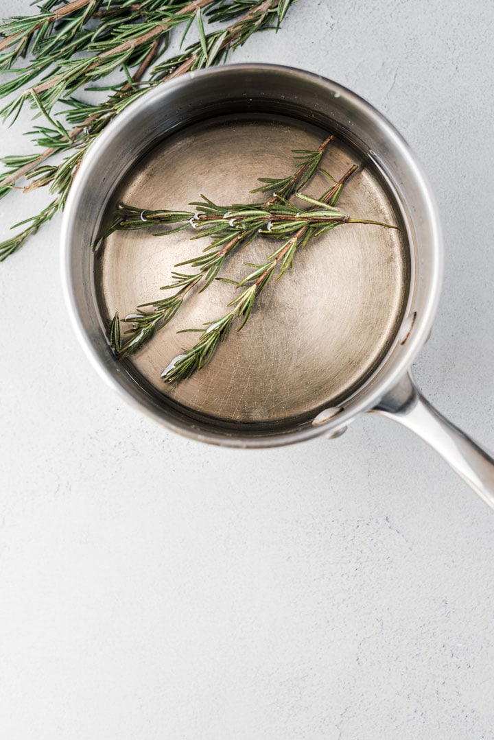 rosemary simple syrup in pot with rosemary sprigs