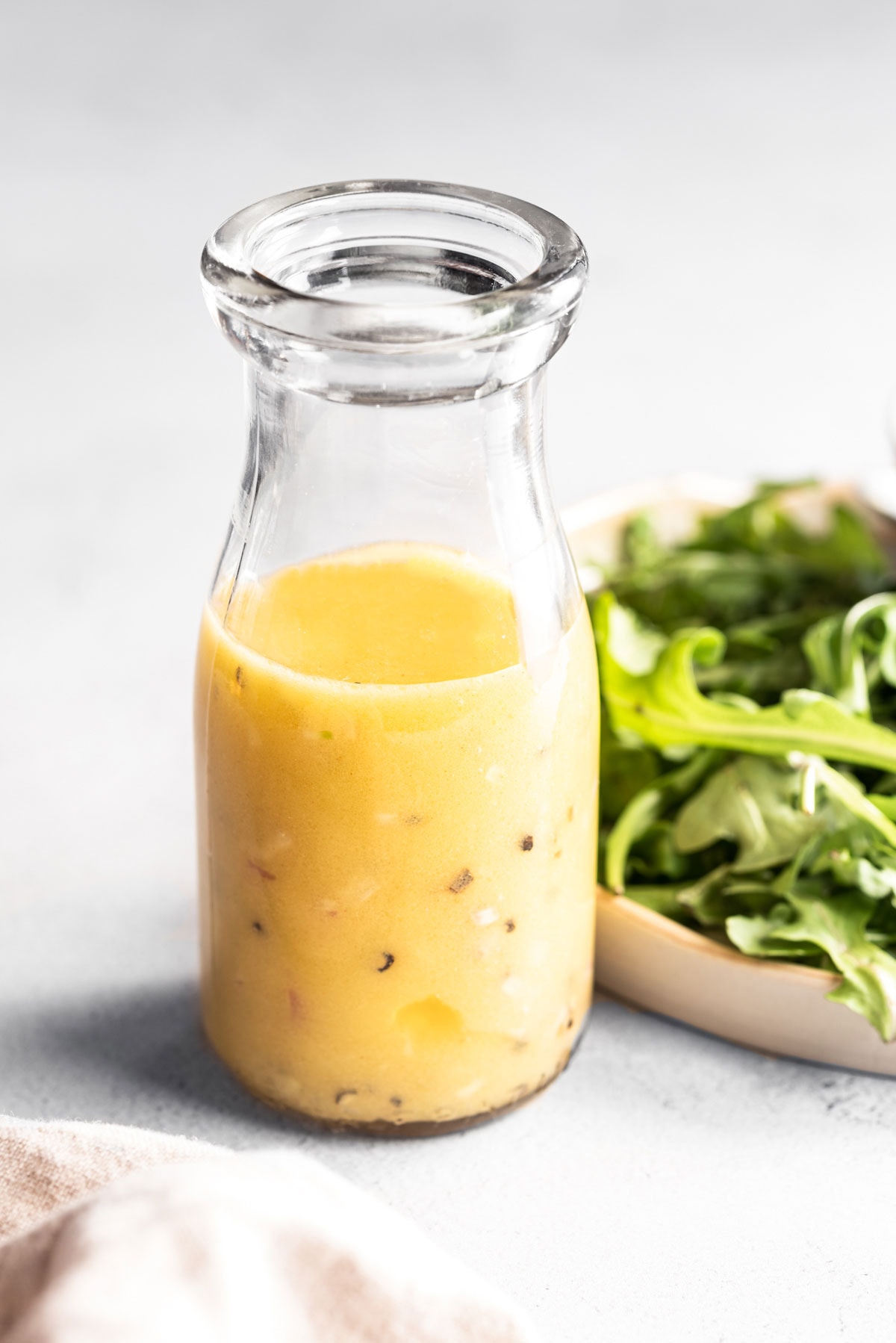 lemon dijon dressing in a jar with greens on plate