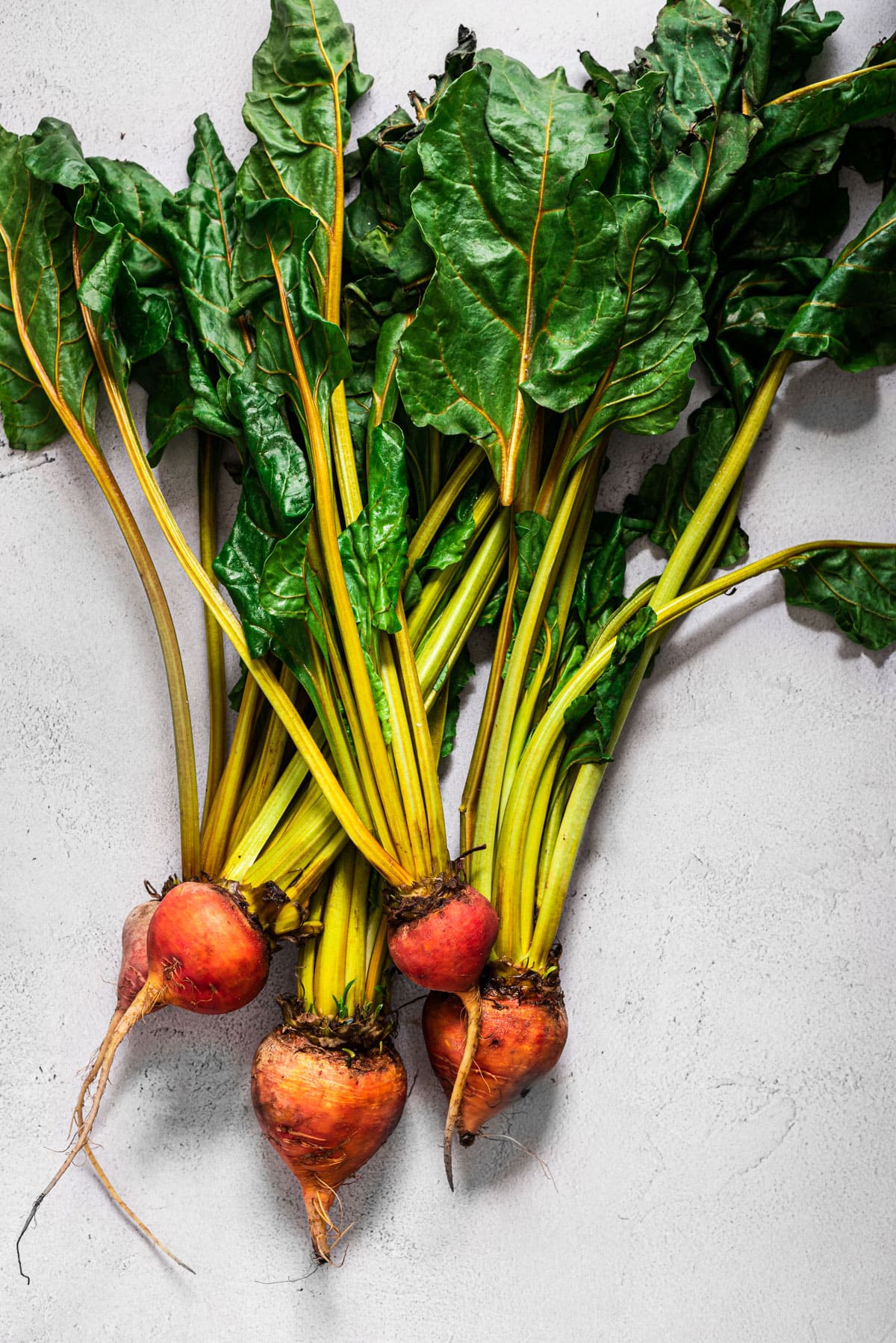 bunch of beets with greens on light background