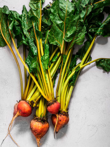 bunch of beets with greens on light background