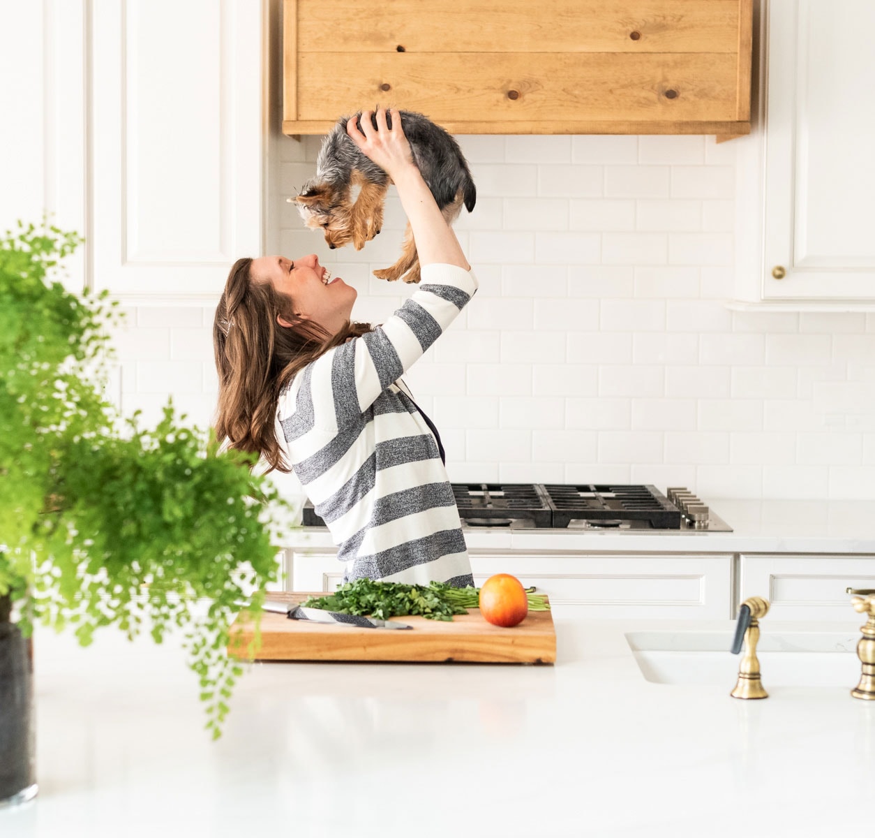 woman holding dog in kitchen