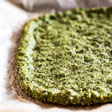 cooked broccoli oat pizza crust on parchment paper close up