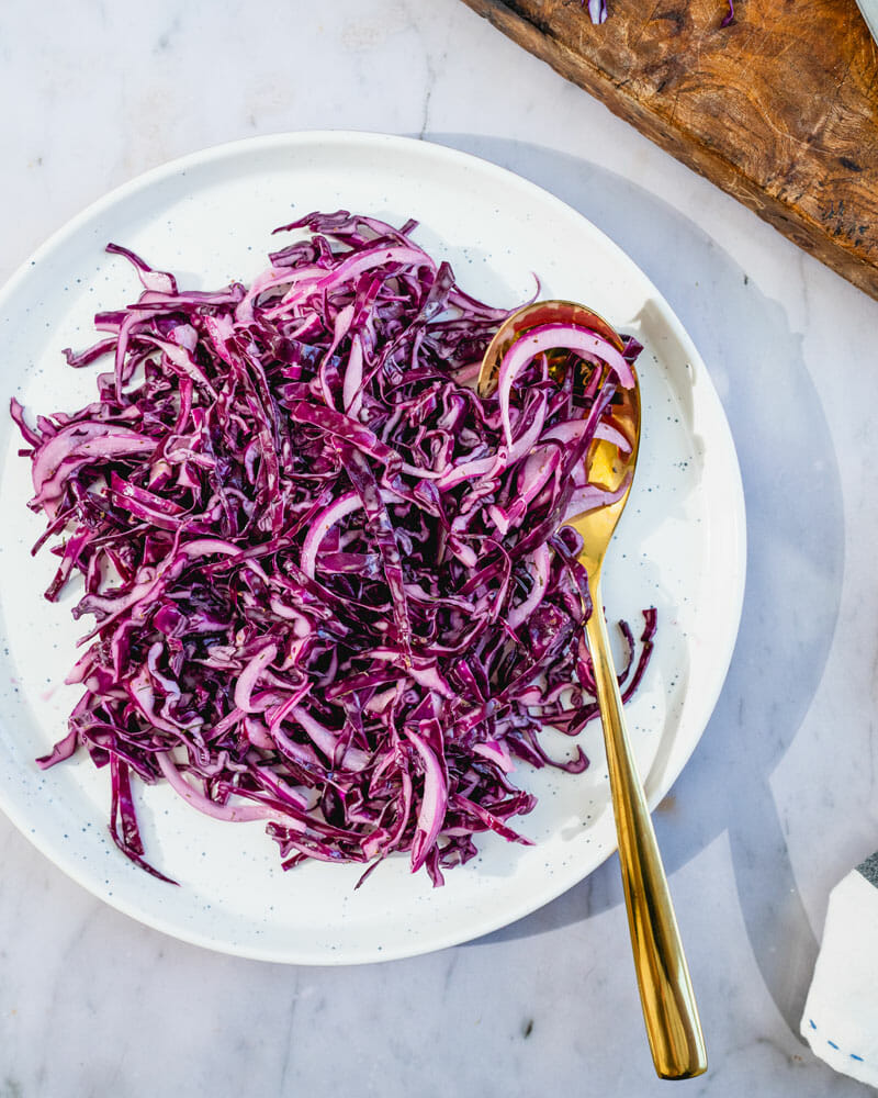 overhead of shredded red cabbage on plate with gold spoon