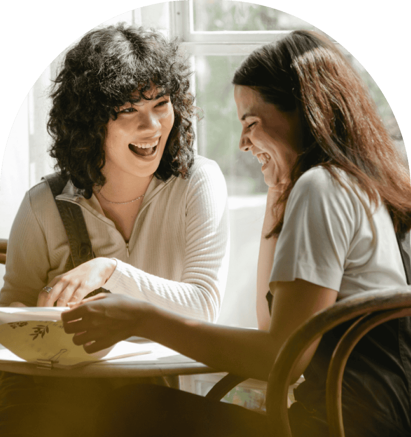 Two girls looking at something together smiling
